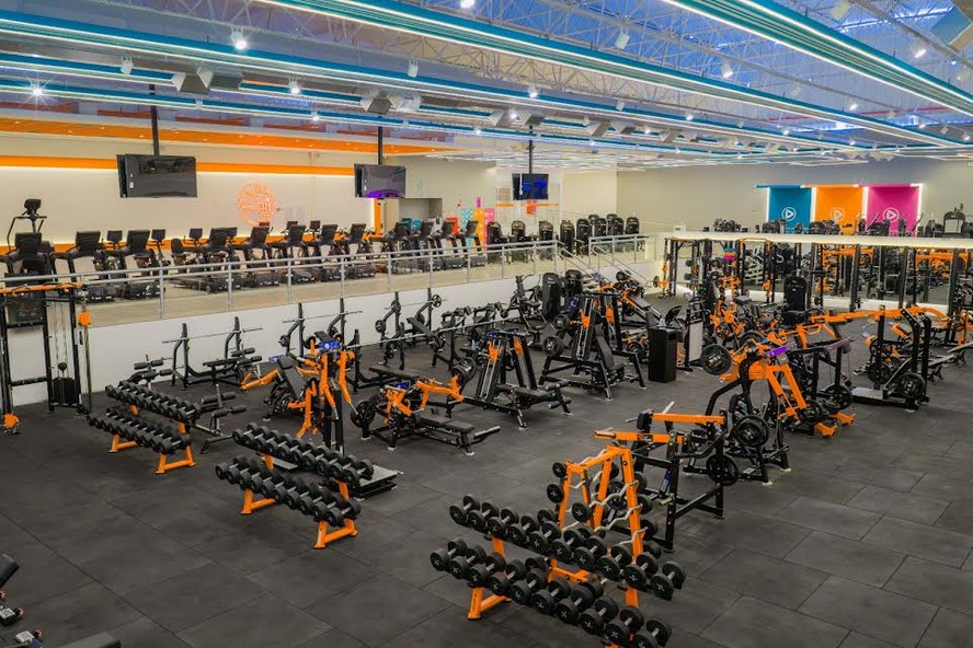 Interior moderno de academia com equipamentos e alunos treinando