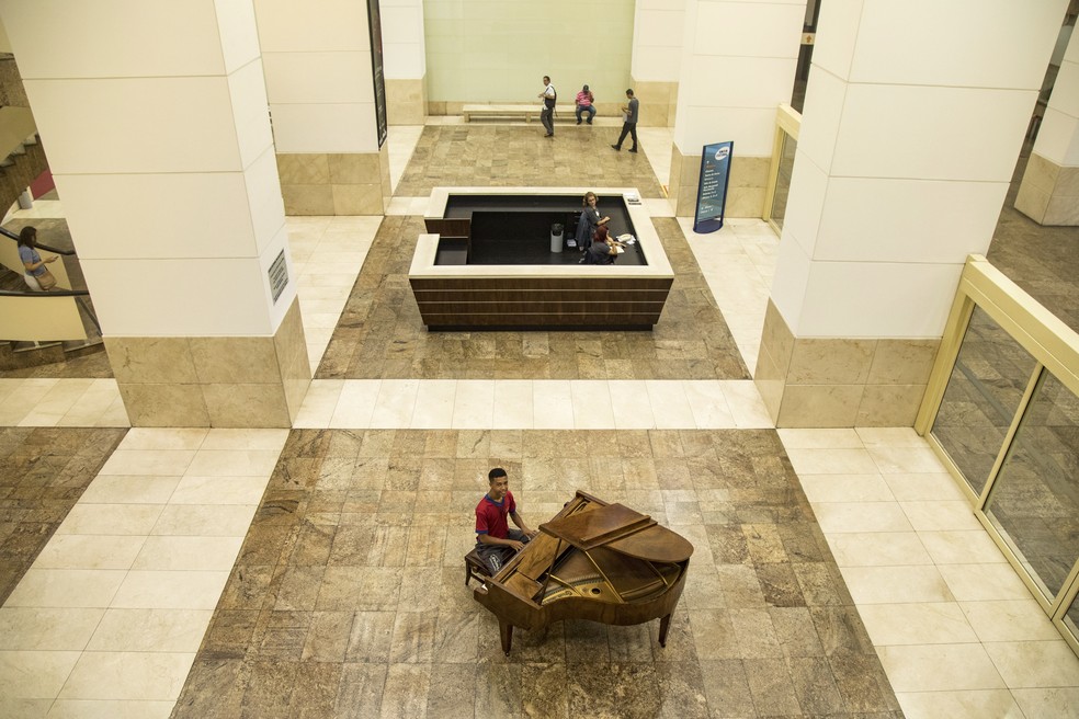 Entregador Lucas Pereira faz pausa para tocar o piano da Caixa Cultural na hora do almoço — Foto: Ana Branco 21/02/2018